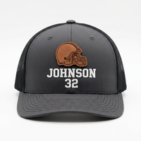 Front view of a custom Richardson 112 charcoal gray snapback hat with a leather patch displaying a football helmet design and personalized name and number in white embroidery